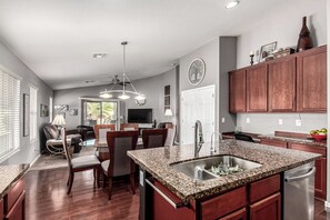 A modern kitchen with granite countertops, a stainless steel sink, and wooden cabinets. - A Maricopa Must: 4BR/3BA Immaculate Home w/Jacuzzi (Maricopa)