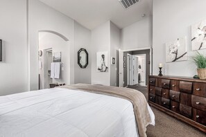 A bedroom with a large bed, a dresser, a mirror, and artwork on the walls. - A Maricopa Must: 4BR/3BA Immaculate Home w/Jacuzzi (Maricopa)