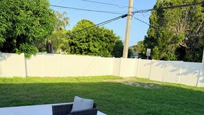 Un área de patio al aire libre con tres sillas de mimbre y una mesa.