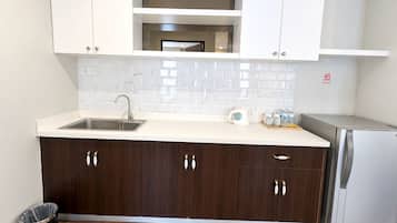 Una cucina moderna con lavello in acciaio inossidabile, pensili in legno scuro, piano di lavoro bianco e forno integrato.