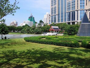 A park with a pavilion, a lake, and modern buildings in the background. - CASA Sukhumvit 39 (Bangkok)