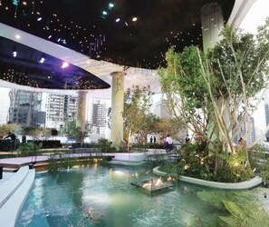 An indoor atrium with a central water feature, surrounded by greenery and modern architecture. - CASA Sukhumvit 39 (Bangkok)