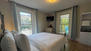 Une chambre à coucher comprenant un lit, une télévision, une commode et une fenêtre donnant sur l’extérieur.