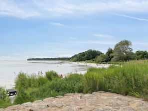 A beach with a stone wall in the foreground, a sandy shore, and trees in the background. - "Toivo" - 300m from the sea by Interhome (Nexø)