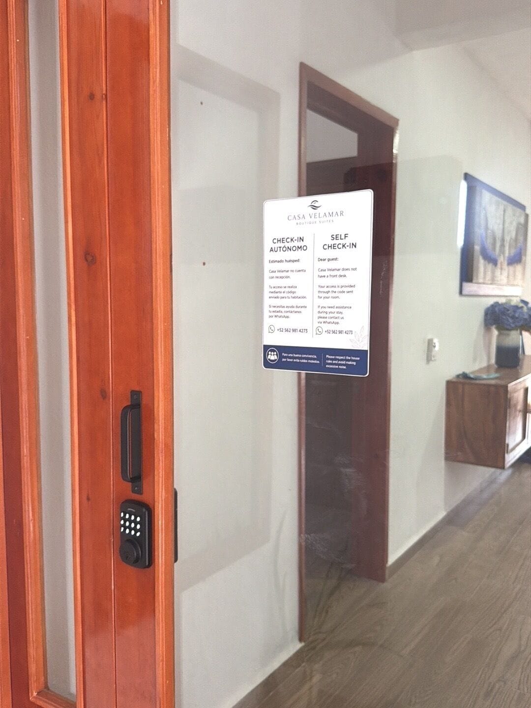 A hotel entrance with a check-in sign, a self-check-in option, and a door with a keypad lock.