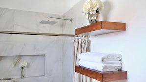 A bathroom with a shower, a towel rack, and a vase with flowers.