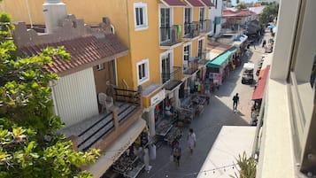 A street view with buildings, balconies, and outdoor market stalls.