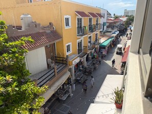 A street view with buildings, balconies, and outdoor market stalls. - CASA VELAMAR (Isla Mujeres)