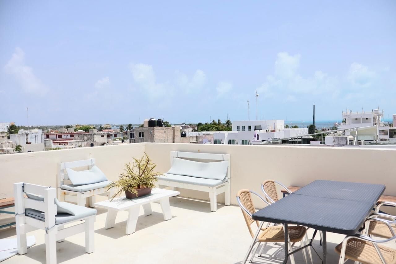 Eine Dachterrasse mit weißen Möbeln, einem Tisch und einem Blumentopf.