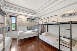 A bunk bed room with a wooden floor, a window, and a door. - Chill Inn Lipa Noi Hostel and Beach Cafe (Koh Samui)