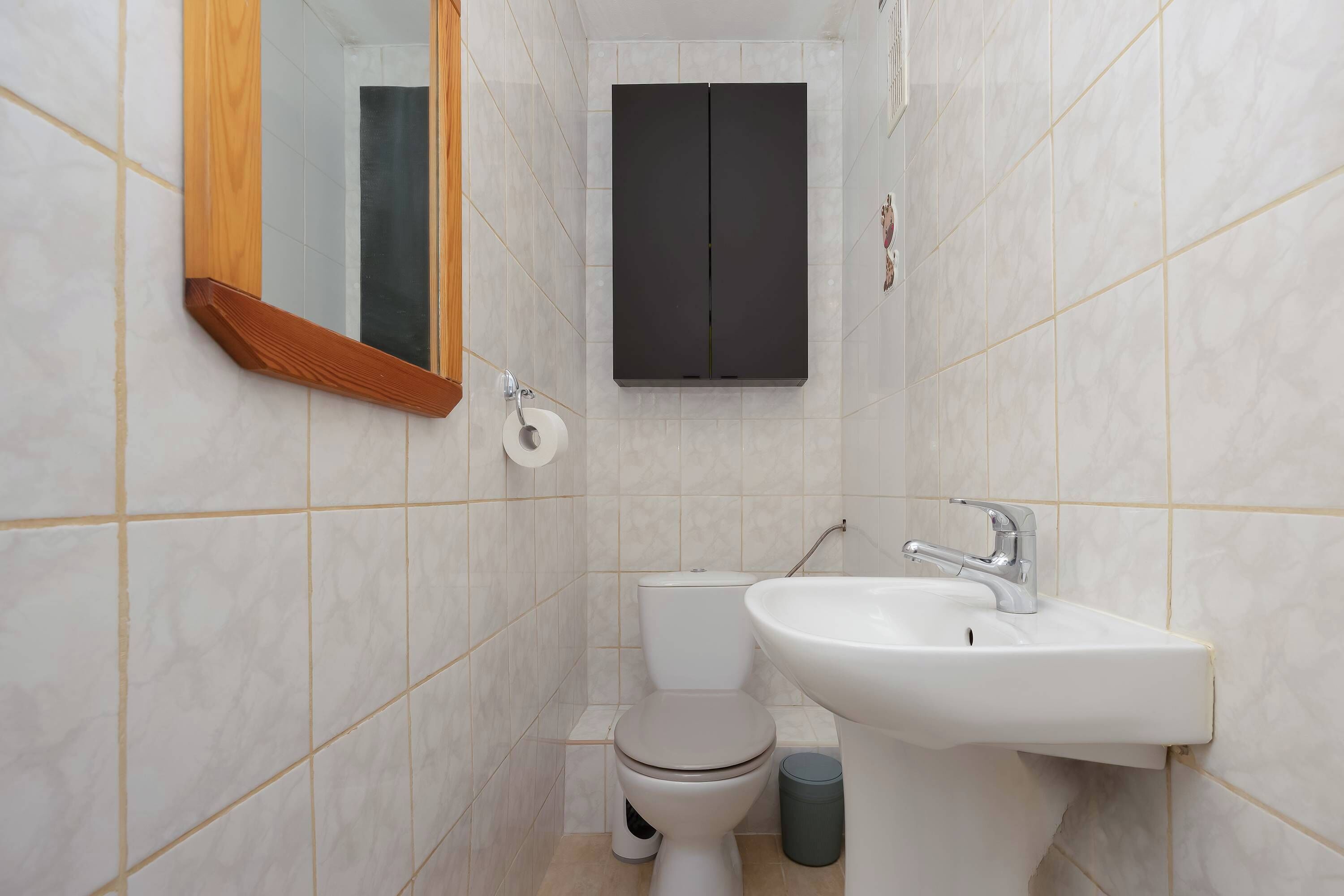 Een badkamer met toilet, wastafel, spiegel en kast.
