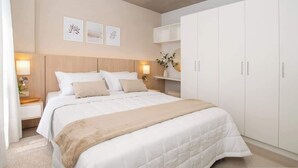Ein Schlafzimmer mit Bett, Nachttischlampen, einem Nachttisch, einem Kleiderschrank und Wandbildern.
