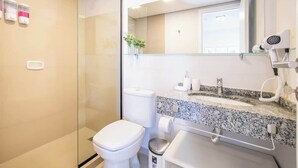 Ein modernes Badezimmer mit einer Duschkabine aus Glas, einer weißen Toilette, einem Waschtisch mit Granitplatte und einem Spiegel über dem Waschbecken.