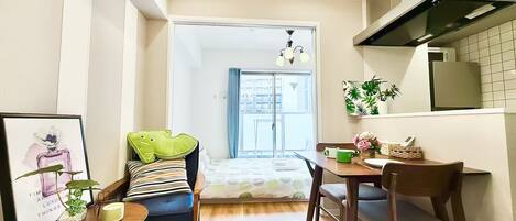 A compact living space with a kitchenette, a dining area, and a bed with a view.