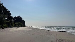 A beach with a clear sky, calm sea, and a sandy shore.