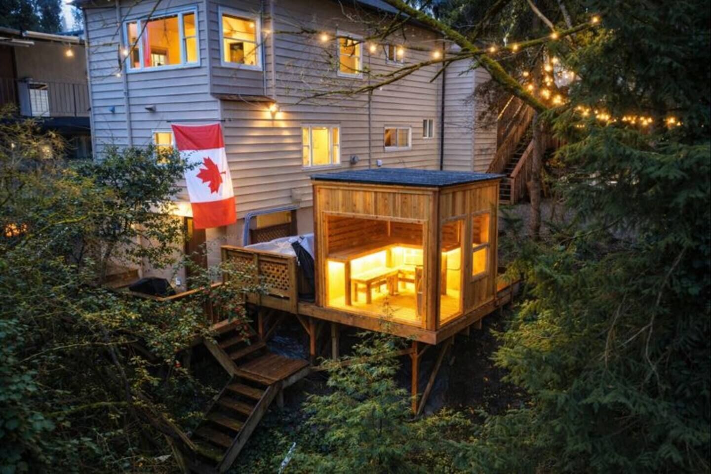 A wooden cabin with a deck, a flag, and string lights.