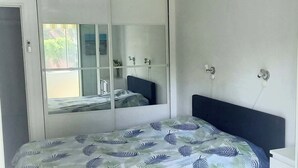 Ein Schlafzimmer mit einem Bett, einem Schrank mit Spiegeln und einem Fenster mit Blick.