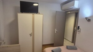 Un dormitorio con armario, cama, aire acondicionado y ventana con persianas.