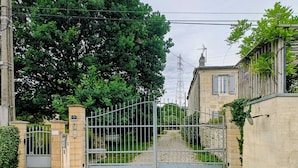A gated entrance with a gravel path leading to a building with stone walls and a metal gate. - Just 9 minutes from Bordeaux: a getaway along the Garonne River at the 4-star Latresne vacation rental (Latresne)