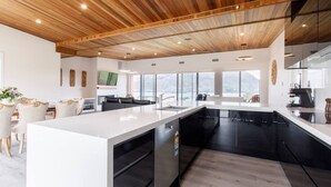 Une cuisine moderne avec un îlot central, des meubles de couleur noire et un plafond en bois.