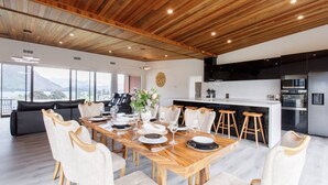 Une cuisine moderne avec un plafond en bois, un coin repas doté d’une table en bois et une vue sur l’extérieur.
