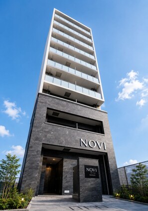 A modern high-rise building with a prominent 'NOVI' sign at the entrance. - NOVI Dotonbori  (CHUO-KU OSAKA)