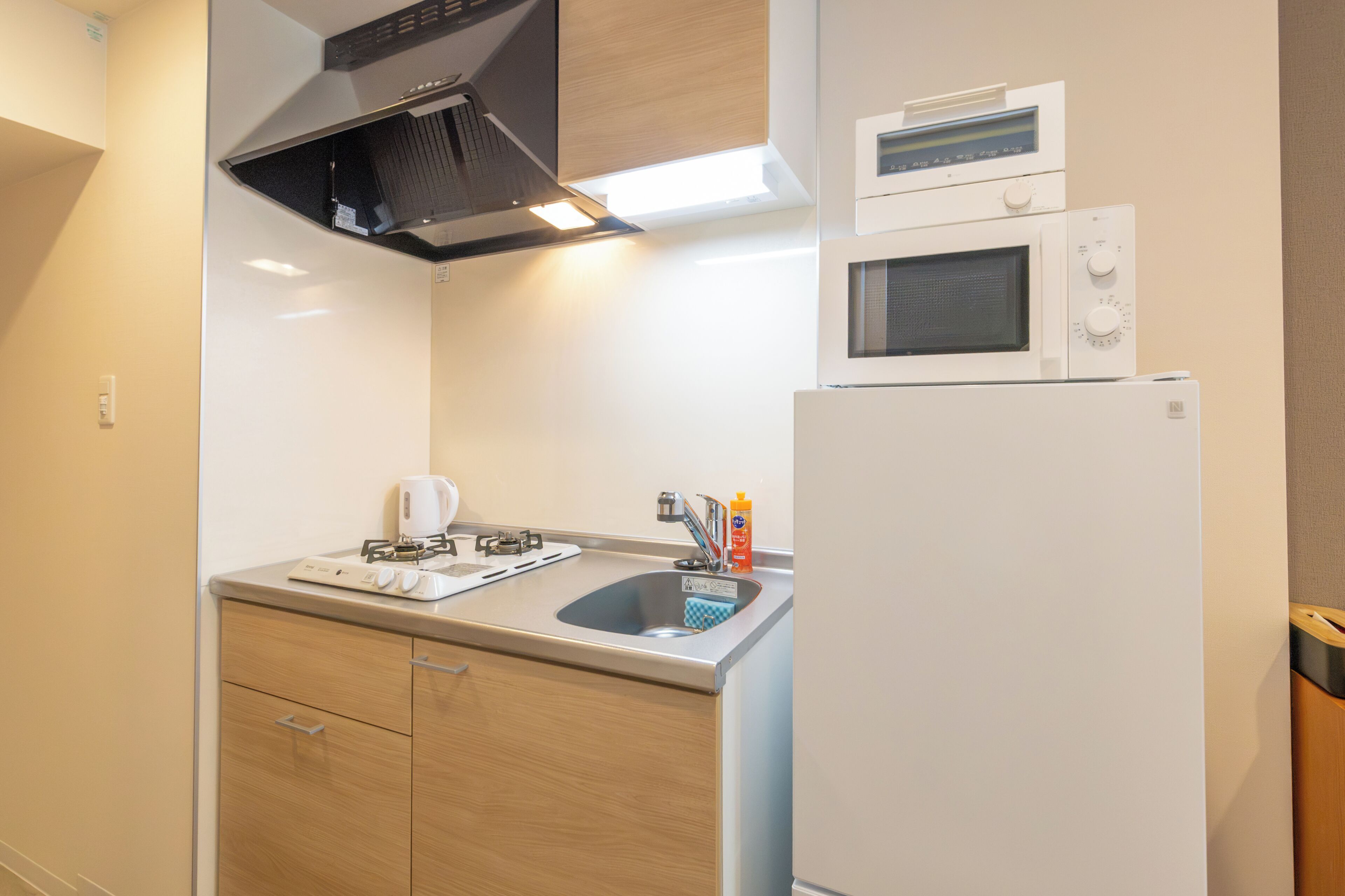 A compact kitchen with a gas stove, a microwave, and a refrigerator.