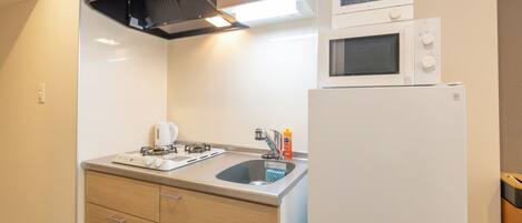 A compact kitchen with a gas stove, a microwave, and a refrigerator.