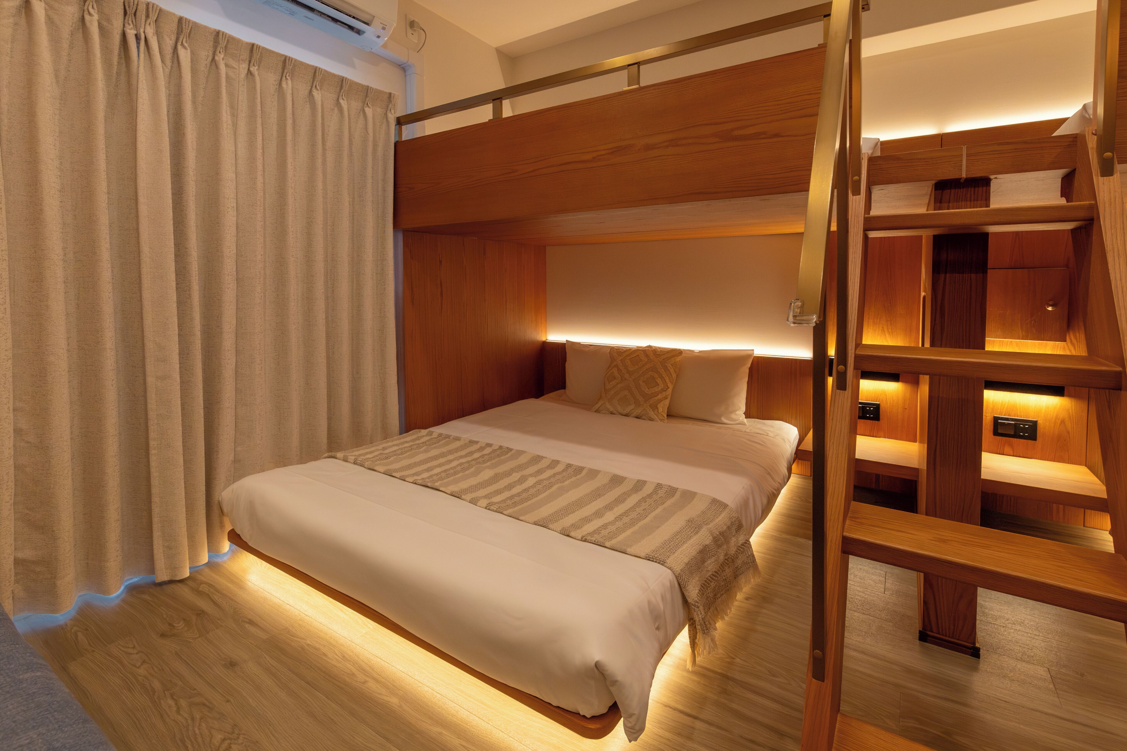 A bunk bed room with a wooden ladder, a bedside table, and a curtain.