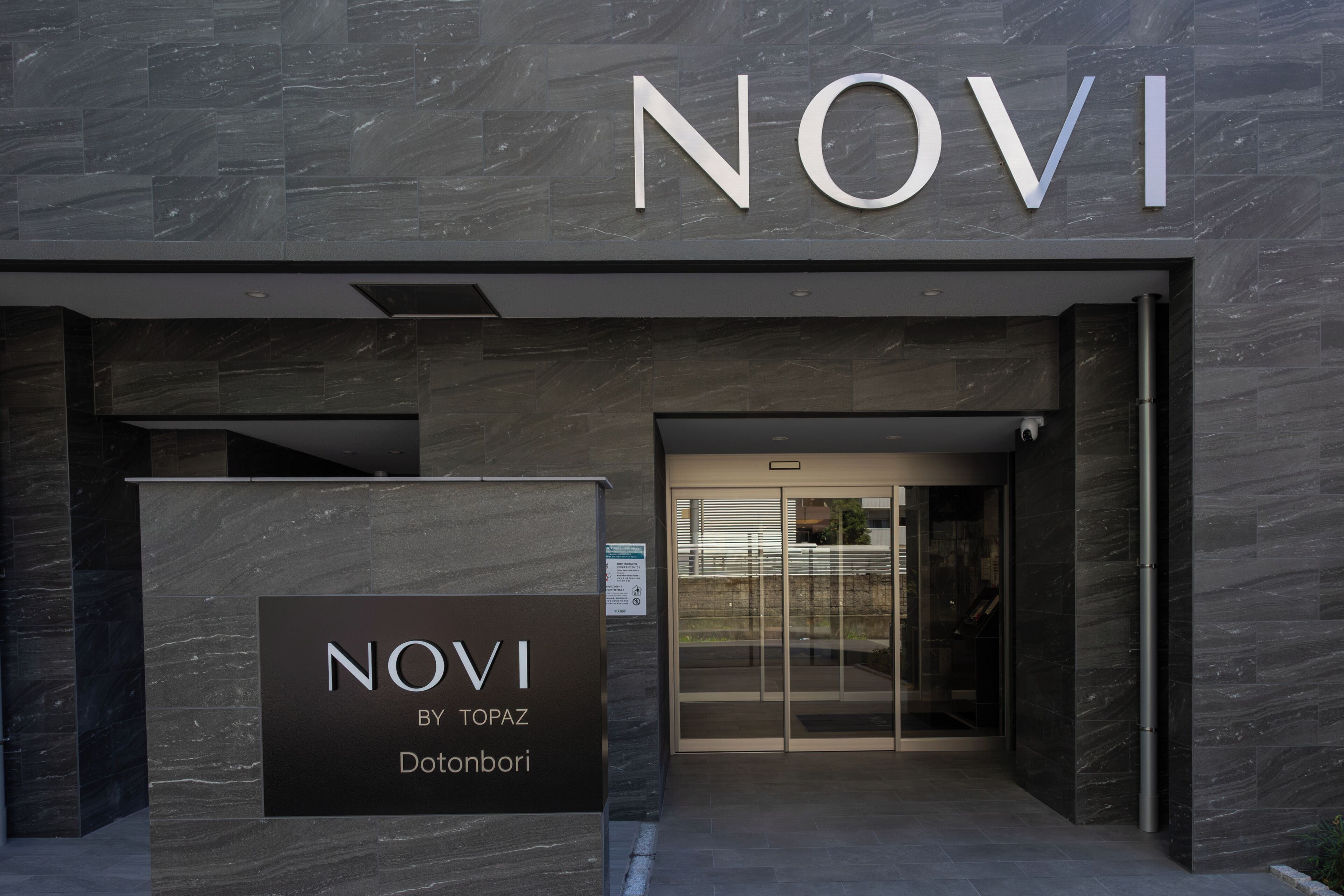 The entrance to a building with a sign that reads 'NOVI BY TOPAZ Donbori'.