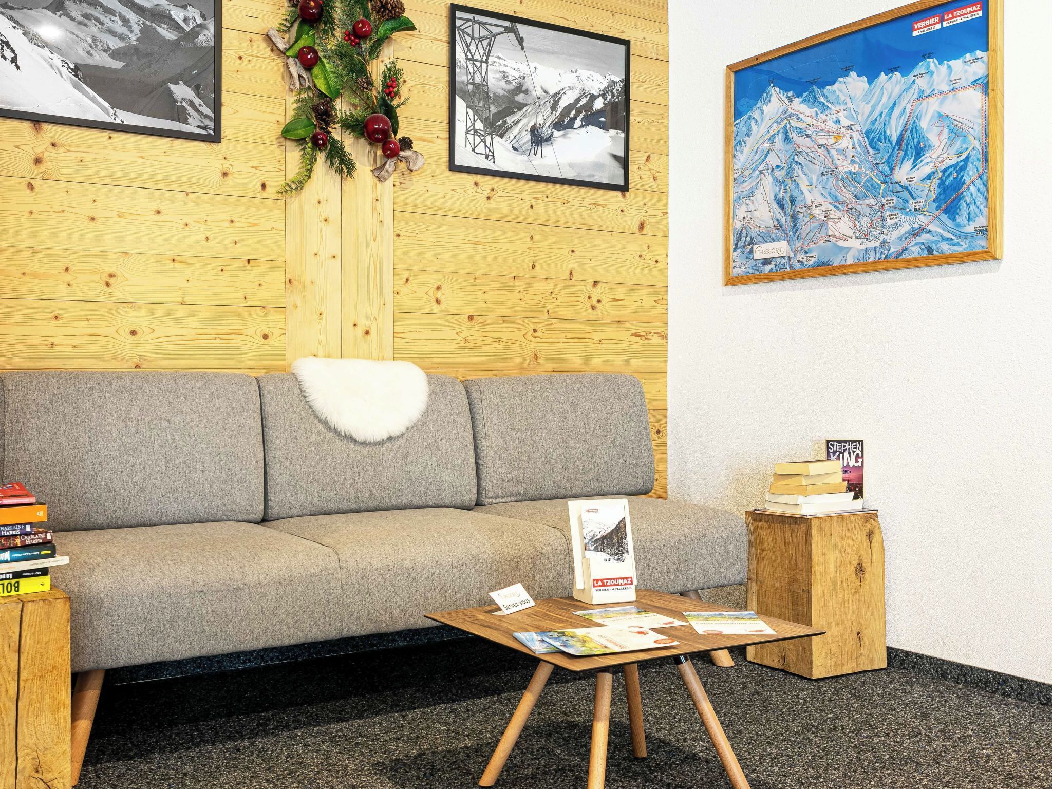 Una habitación acogedora con un sofá gris, una pequeña mesa de madera con folletos y un mapa enmarcado en la pared.