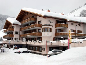 A multi-story hotel with balconies, a ski slope in the background, and snow-covered surroundings. - Nauer, (St. Antönien), nauer_stantoenien by Interhome (St. Antönien)