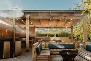 Une terrasse extérieure équipée d’un barbecue, de sièges et offrant une vue sur l’extérieur.