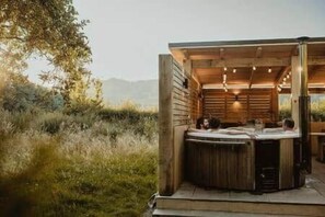 A wooden cabin with a hot tub and a view of the surrounding landscape.