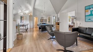 Ein geräumiges Wohnzimmer mit Billardtisch, einer Couch und einem Essbereich.