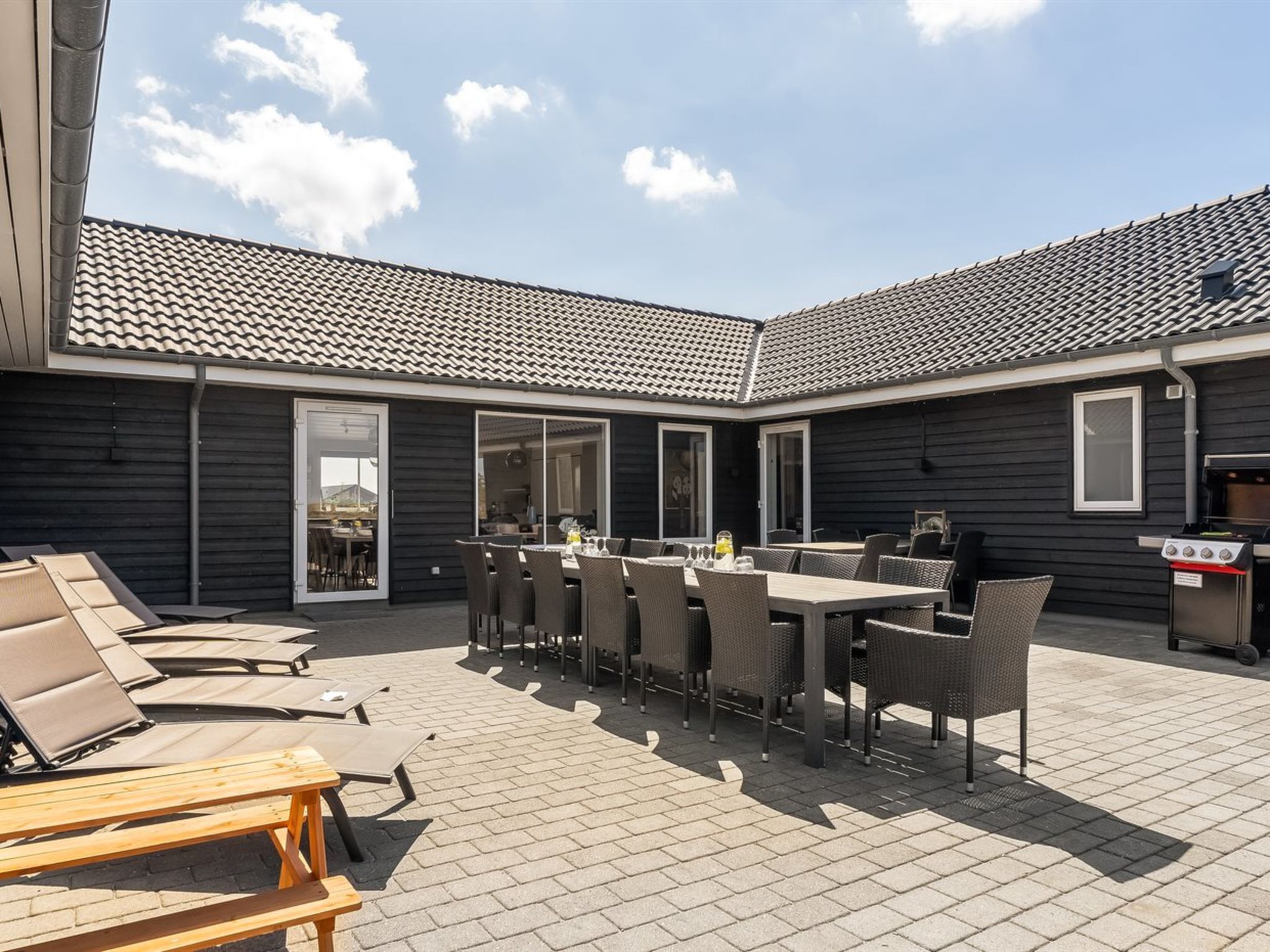 Eine Terrasse mit Tisch, Stühlen, einem Grill und Blick zum Himmel.