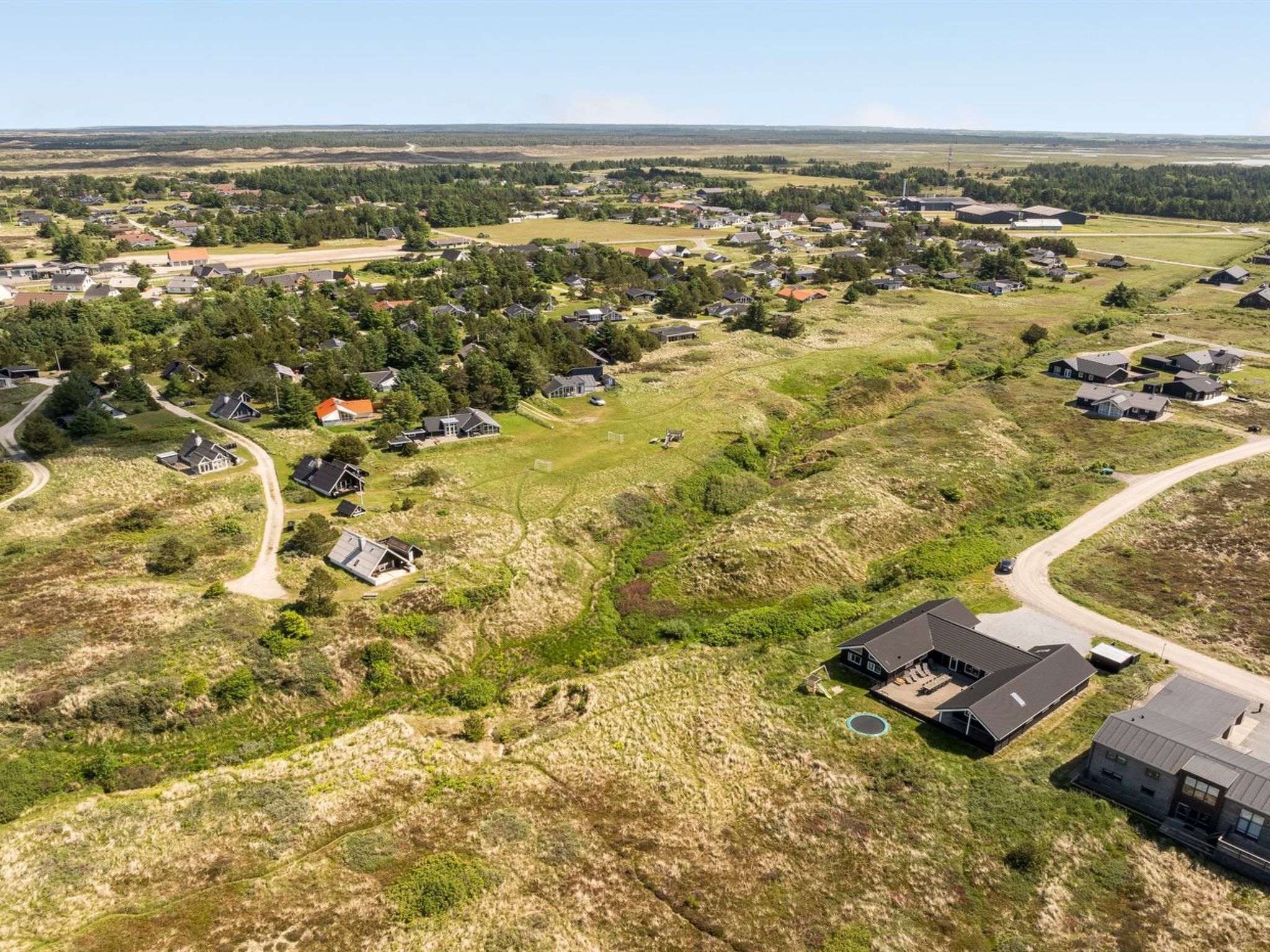 Vue aérienne d’un quartier résidentiel avec des maisons, des routes et la végétation environnante.