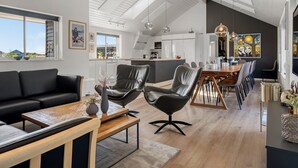 Ein modernes Wohnzimmer mit einer schwarzen Ledersofa, einem Holztisch und einem Essbereich mit einem Holztisch und Stühlen.