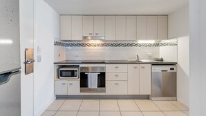 Eine kleine Küche mit weißen Schränken, Mikrowelle, Backofen, Spüle und Geschirrspüler.