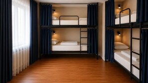 A bunk room with wooden flooring, two bunk beds, and a window with curtains. - Nice hostel in Mongolia (Ulaanbaatar)