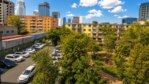 A cityscape with multi-story buildings, a parking lot, and green trees. - Nice hostel in Mongolia (Ulaanbaatar)