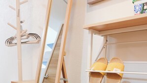 Ein Zimmer mit Holzboden, einem Spiegel, einem Schuhregal mit Hausschuhen und einer kleinen Holzkabine.