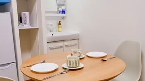 Ein Essbereich mit einem runden Holztisch, weißen Stühlen und einer weißen Schrank mit Regalen.