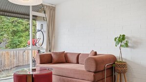 A modern living room with a sofa, a glass coffee table, and a potted plant.