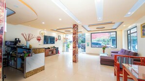 Un hall de hotel con recepción, zona de estar y grandes ventanales.