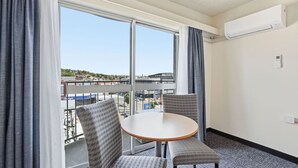 Et hotelværelse med et stort vindue, et rundt bord, to stole og en aircondition.