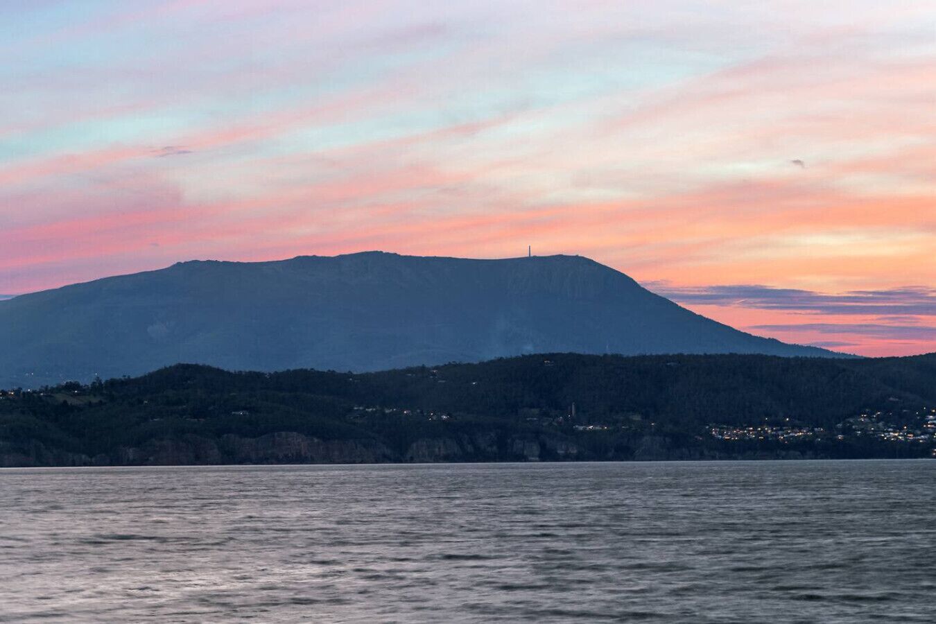 A mountain with a clear sky and a body of water in the foreground.
