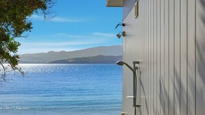 A beachside building with a view of the ocean and distant mountains. - Beachfront Escape + Hot Tub (Opossum Bay)