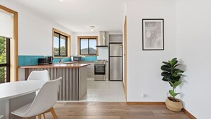 Een moderne keuken met een eethoek, een groot raam en een potplant.