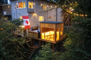 Eine Holzhütte mit einer Veranda, einer Flagge und Lichterketten.
